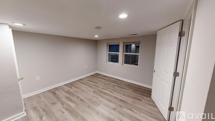 A room with a white door and a window with white blinds.
