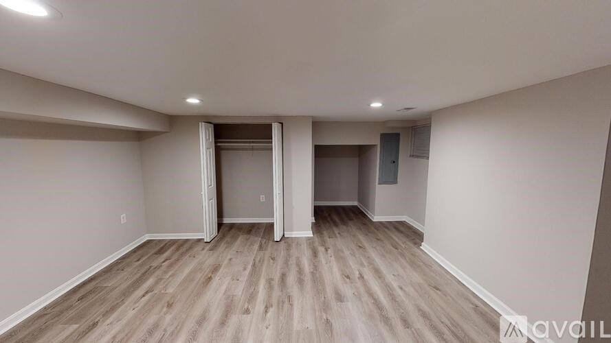 A spacious room with wooden flooring and white walls.
