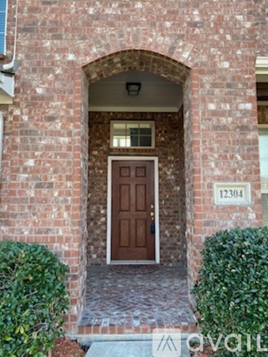 A brown door is at the end of a brick archway.
