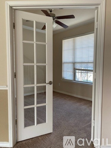 A room with a white door and a ceiling fan.
