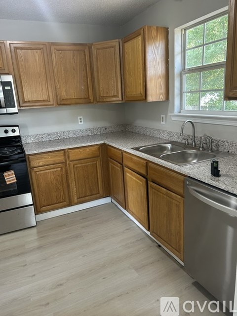 A kitchen with wooden cabinets and a stainless steel dishwasher.