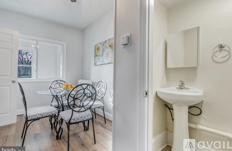 A bathroom with a white sink and a dining table with chairs.