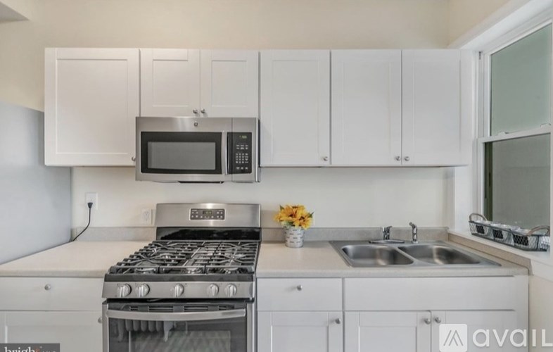 A kitchen with white cabinets and a stove top oven.