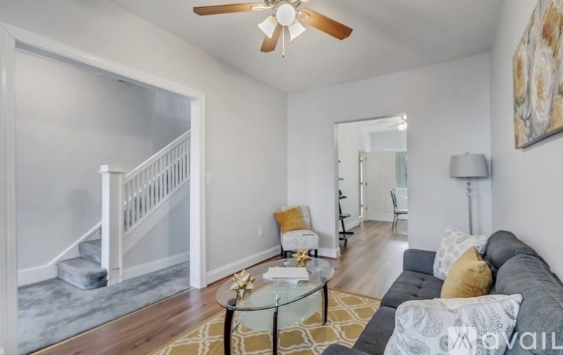 A living room with a couch, a coffee table, and a staircase.