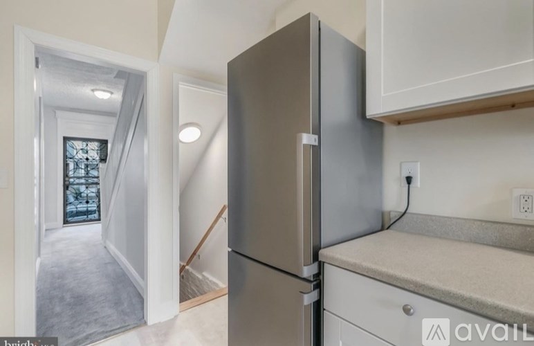 A kitchen with a stainless steel refrigerator and white cabinets.