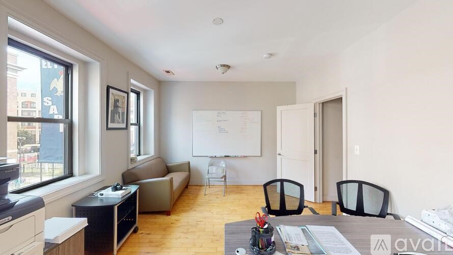 A living room with a couch, chairs, and a whiteboard on the wall.