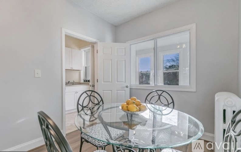 A glass dining table with chairs and a bowl of lemons on it.