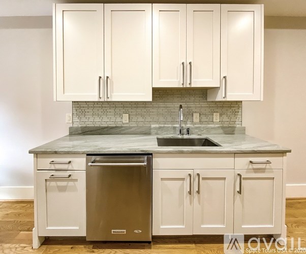A kitchen with white cabinets and a marble countertop.