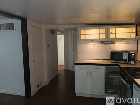 A kitchen with white cabinets and a black counter top.