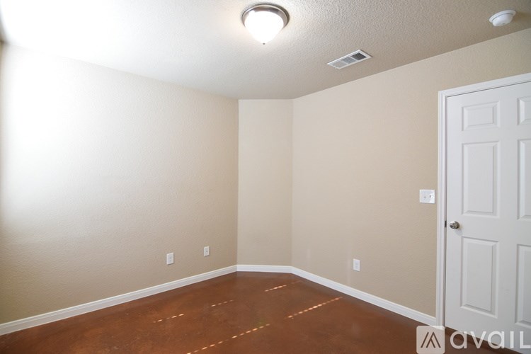 A room with a white door and a brown floor.