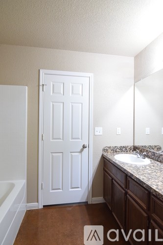 A bathroom with a white door, a sink, and a bathtub.