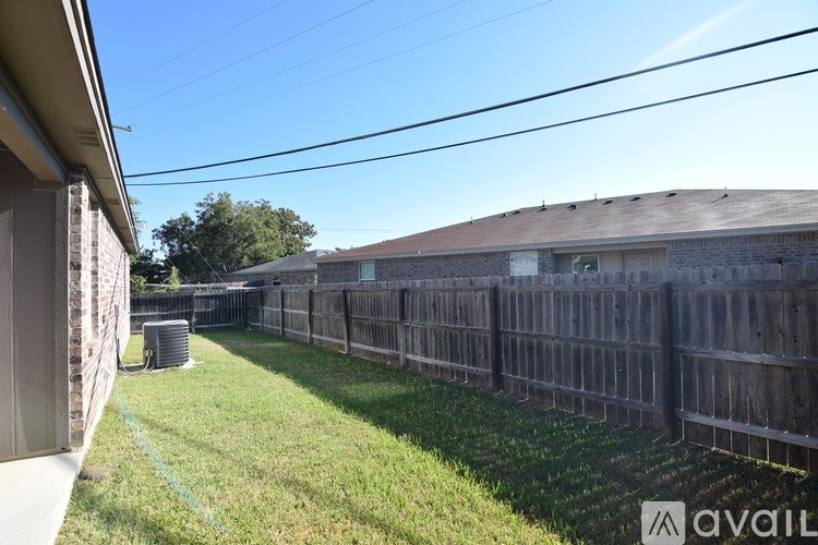 A backyard with a wooden fence and a house in the background.