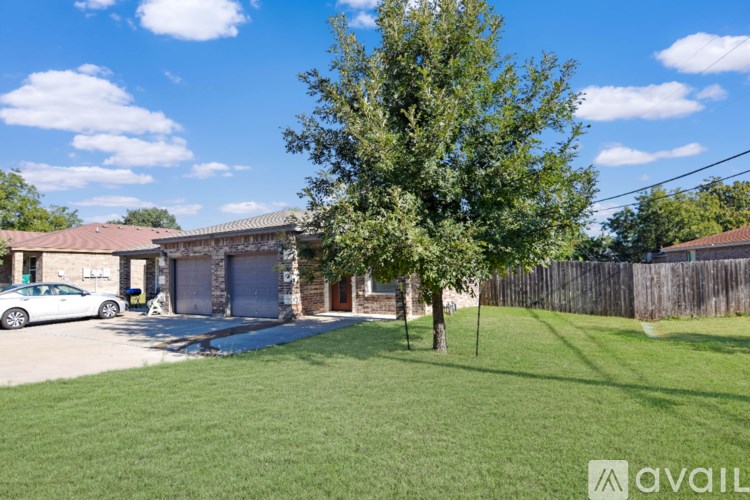 A house with a tree in front and a car parked in the driveway.