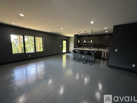 A spacious room with a kitchen area and a dining table with chairs.