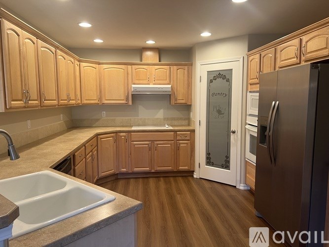 A kitchen with wooden cabinets and a stainless steel refrigerator.