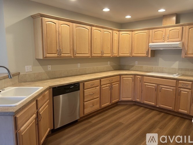 A kitchen with wooden cabinets and a stainless steel dishwasher.