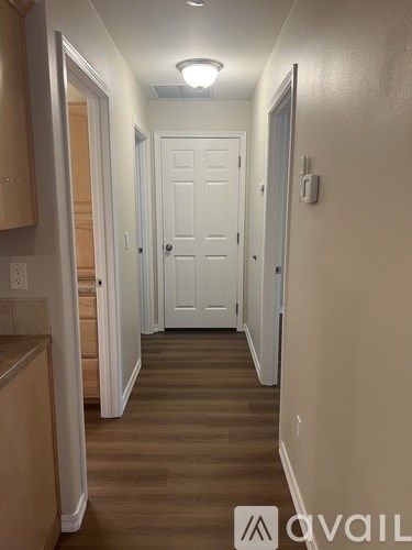A hallway with a white door and wooden floors.