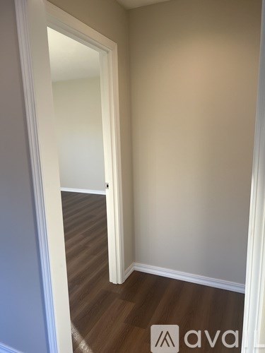 A hallway with a wooden floor and white walls.