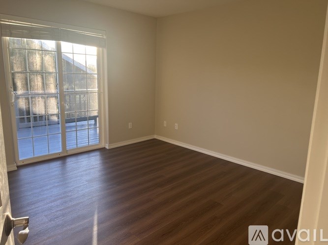 A room with wooden flooring and a large window with blinds.
