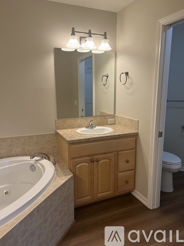 A bathroom with a tub, sink, and mirror.
