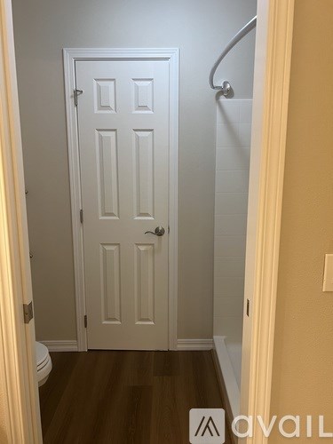 A white door with a silver handle is in a room with wooden floors.