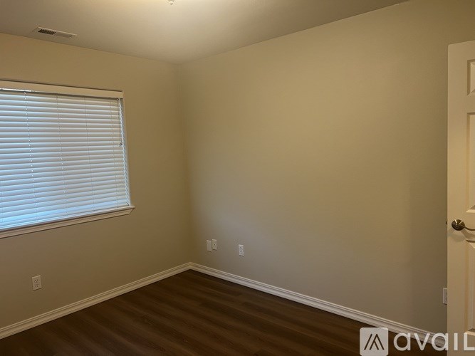 A room with a door, window, and wooden floor.