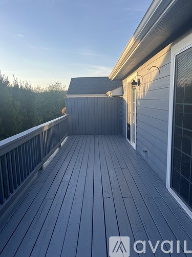 A wooden deck with a railing and a small building in the background.