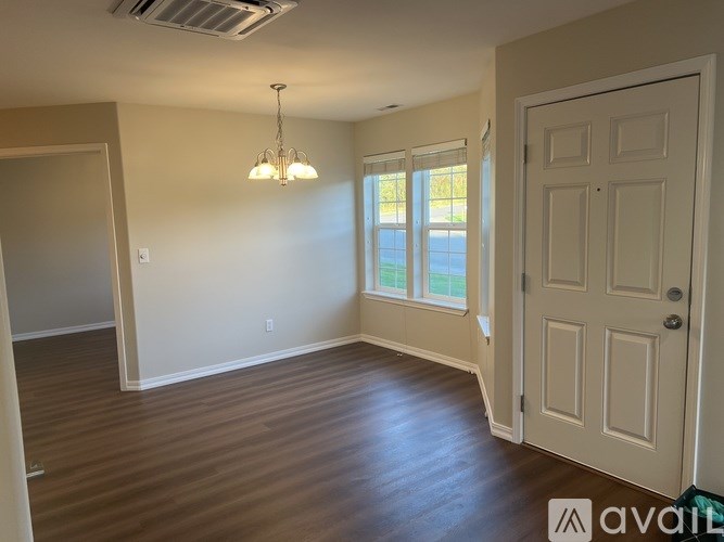 A room with a door, a window, and a chandelier.