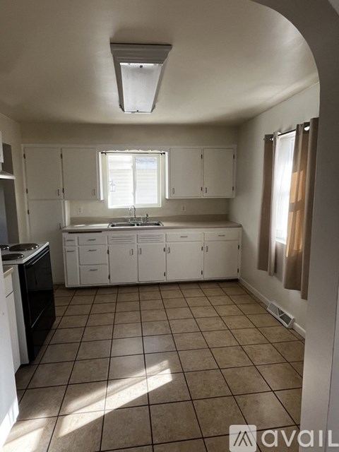 A kitchen with white cabinets and a tiled floor.