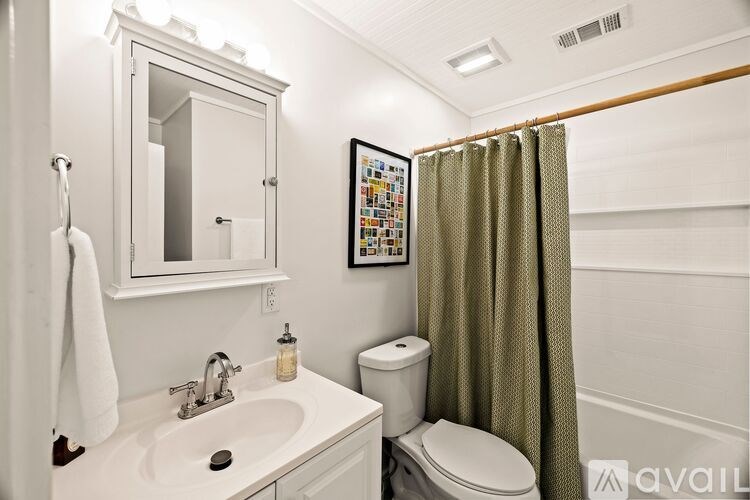 A bathroom with a white sink, toilet, and a mirror above the sink.