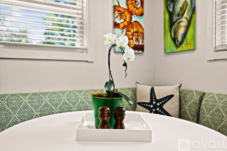 A white table with a flower in a pot and a starfish on the couch.