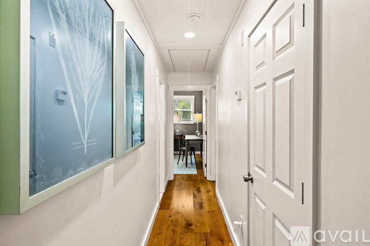 A hallway with a wooden floor and white walls.