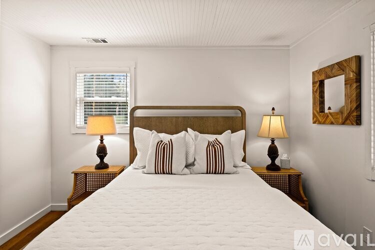 A bedroom with a large bed, two lamps, and a mirror on the wall.