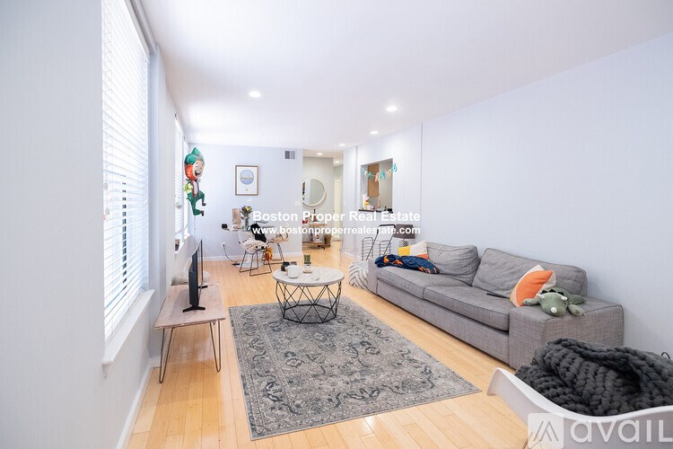 A living room with a grey couch, a black television, and a glass table.