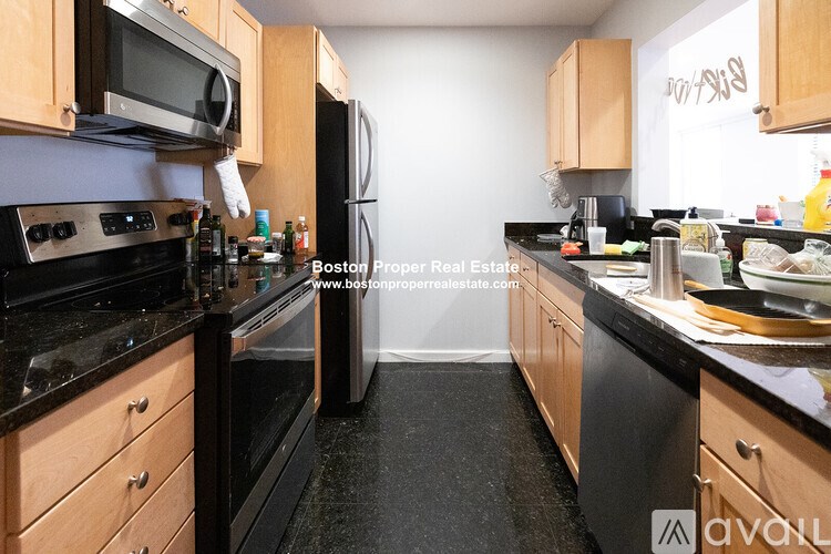 A kitchen with black granite countertops and wooden cabinets.