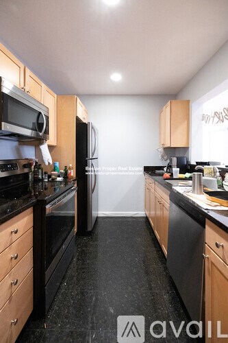 A kitchen with black countertops and wooden cabinets.
