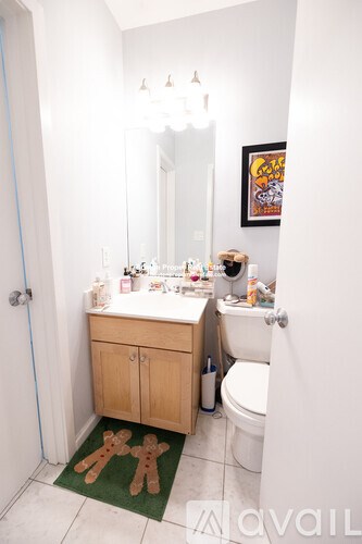 A bathroom with a toilet, sink, and a rug with two gingerbread men on it.