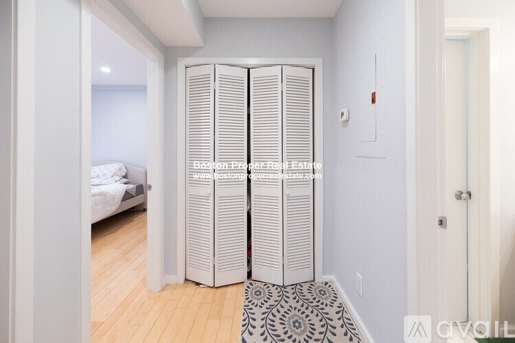 A room with a white door and a black and white patterned rug.