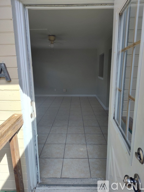 A white door with a fan on the ceiling inside the room.