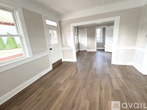 A spacious room with wooden flooring and white walls.