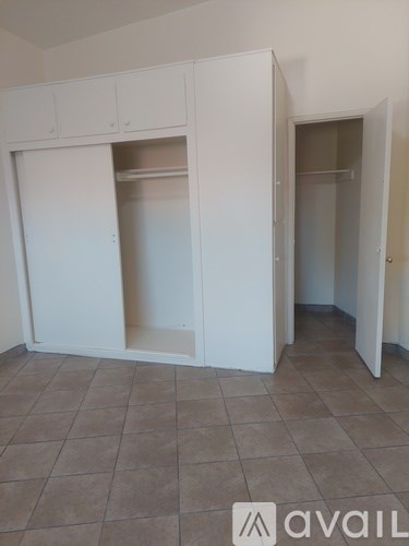 A room with white cupboards and a tiled floor.
