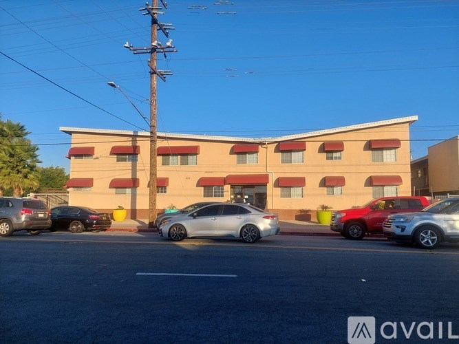 A parking lot with cars and a building with a red awning in the background.
