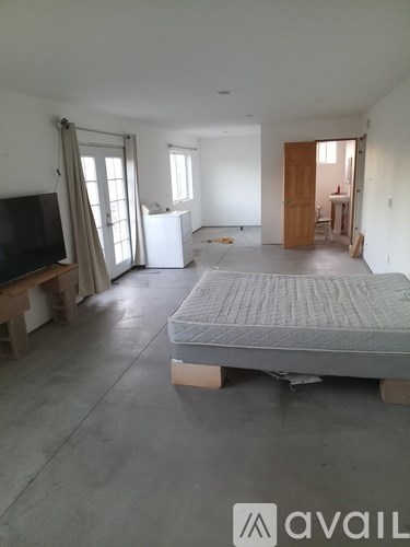 A bedroom with a bed, television, and a window with curtains.