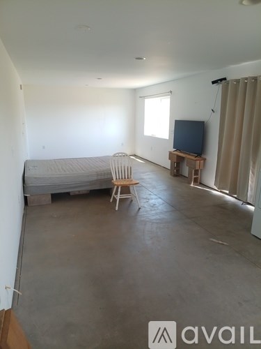 A living room with a grey sofa, a wooden chair, and a television on a wooden stand.