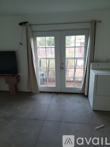 A room with a television, a window with curtains, and a white cabinet.