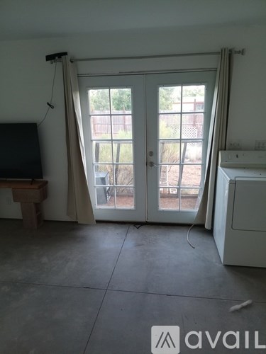A room with a television, a window with curtains, and a white cabinet.