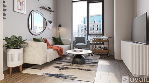 A modern living room with a large window, a white sofa, and a TV on the wall.
