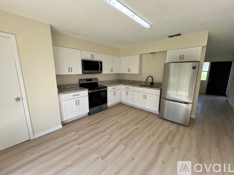 A kitchen with white cabinets and a wooden floor.