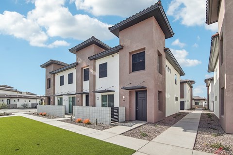 A row of houses with a green lawn in front.