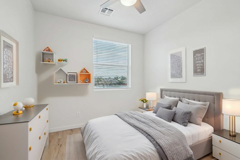 A bedroom with a bed, nightstand, and a dresser with decorative items on top.